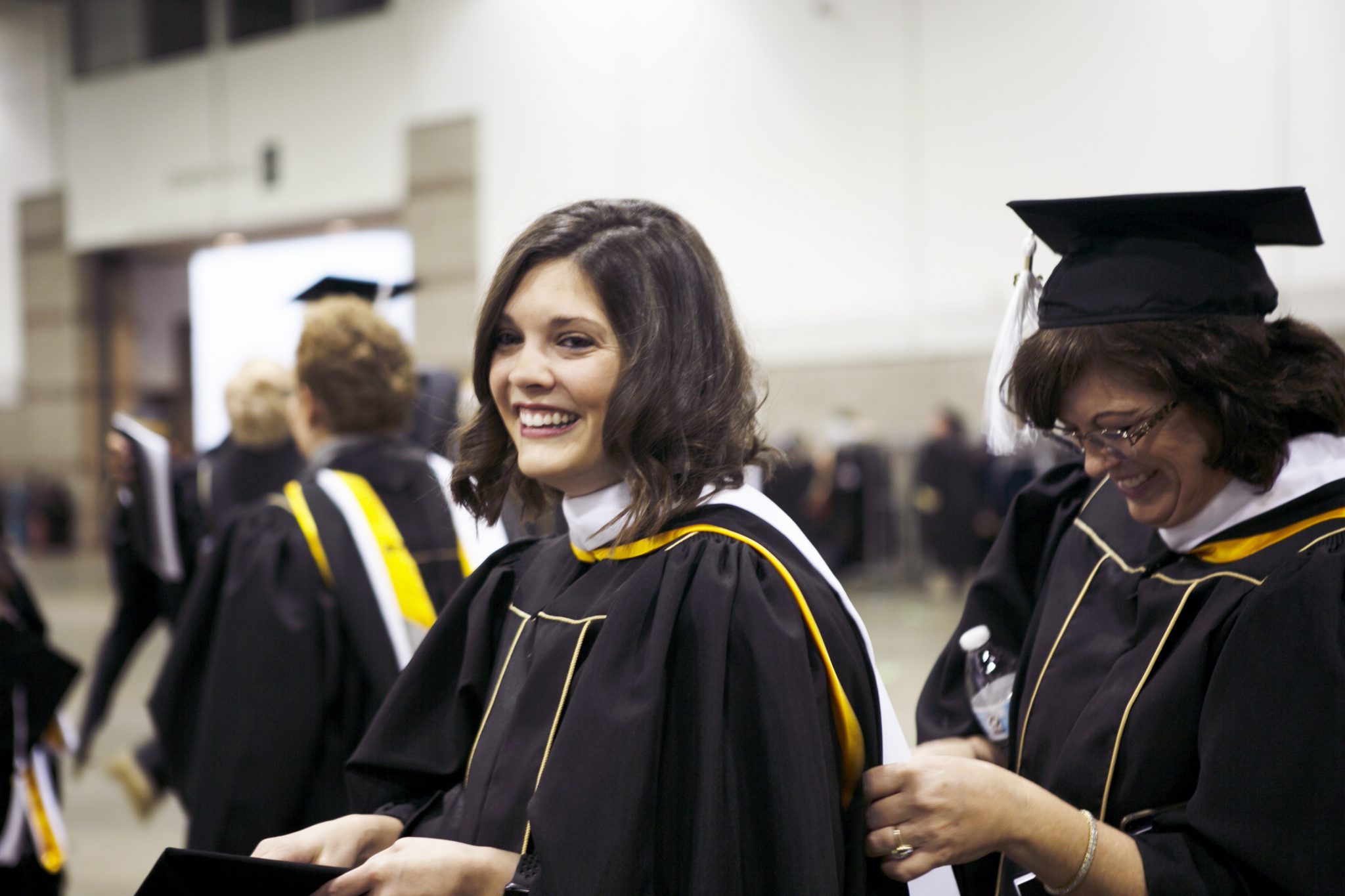 Student helping another with robe during fall commencement 2018