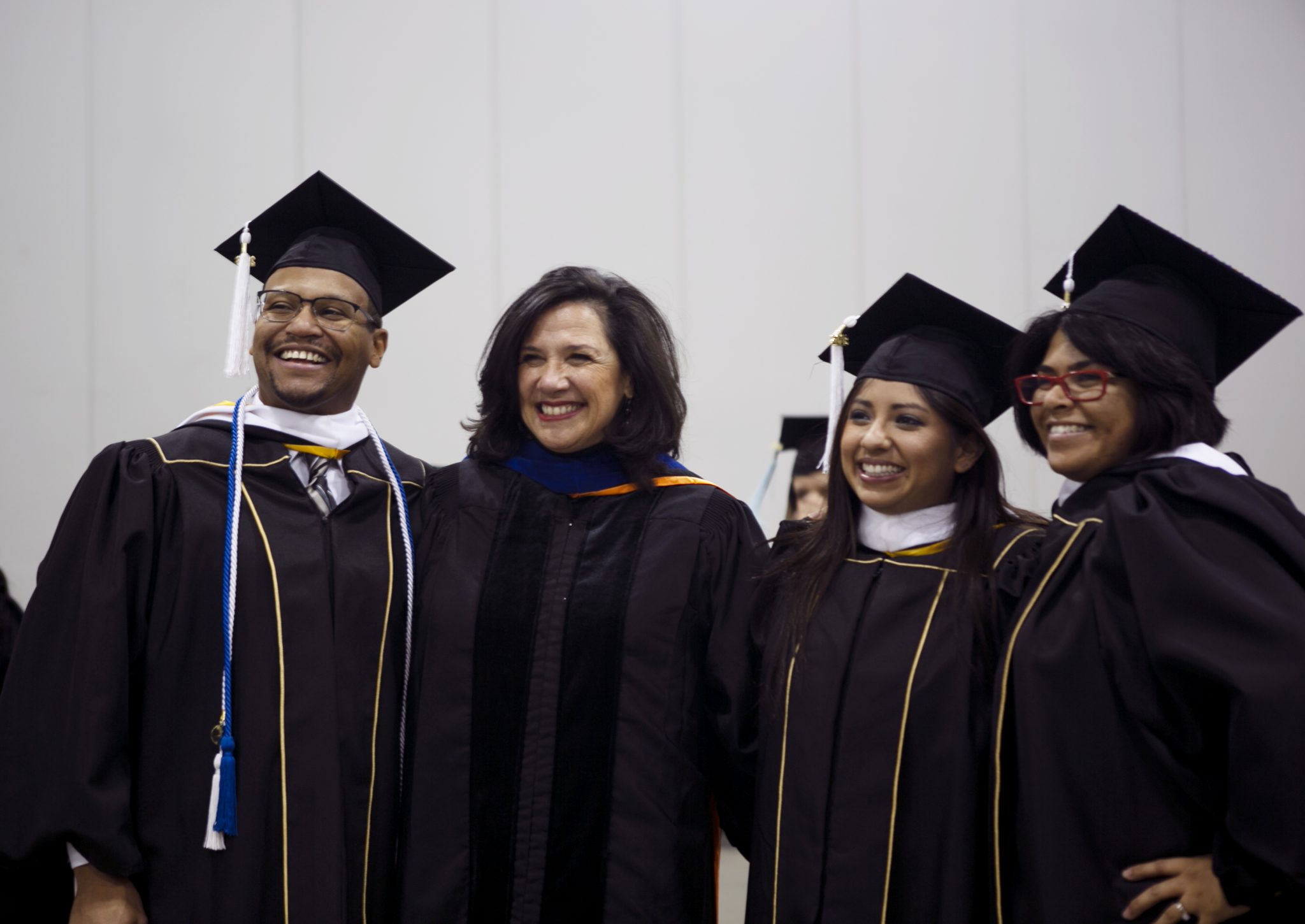 three students with their professor wearing grad regalia at fall commencement 